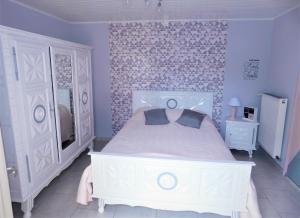 a bedroom with a white bed and a purple wall at Chambre du Hamel in Avroult