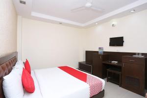 una camera da letto con un letto con cuscini rossi e una TV di Collection O Haridwar Railway Station Formerly Le Central a Haridwār