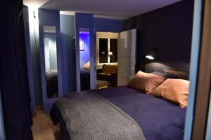 Schlafzimmer mit blauen Wänden und einem Bett mit lila Bettwäsche in der Unterkunft La Bellevue, maison entière in Hénouville