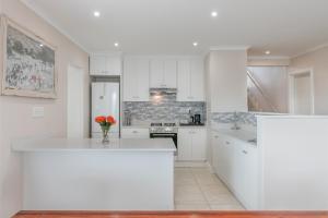 a white kitchen with a vase of flowers on a counter at Pezula Afternoon Delight NT3 in Knysna