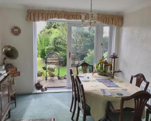 een eetkamer met een tafel en een groot raam bij Holly House B&B in Sittingbourne