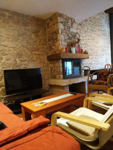 a living room with a tv and a stone wall at Casa Rural La Veterinaria in Aldeadávila de la Ribera