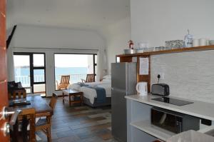 a room with a kitchen and a bedroom with a bed at The Cormorant House in Lüderitz