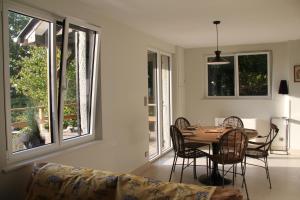 - une salle à manger avec une table, des chaises et des fenêtres dans l'établissement La Bellevue, maison entière, à Hénouville