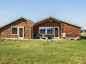 a log cabin with a porch and chairs in a field at 10 person holiday home in Harbo re in Harboør