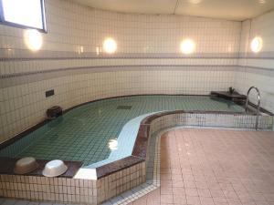 einem großen Pool in einem Gebäude mit einer Kachelwand in der Unterkunft Castle Inn Komaki in Komaki