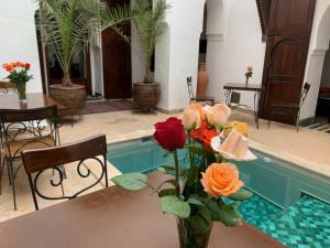 a vase of flowers on a table next to a pool at Riad Nora in Marrakesh