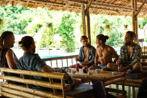 eine Gruppe von Menschen, die um einen Tisch sitzen in der Unterkunft Woodstock Jungle Camp in Cát Bà