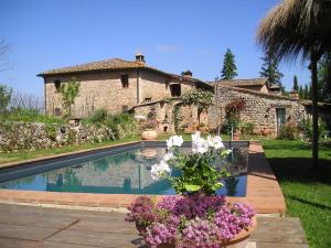 een huis met een zwembad met bloemen ervoor bij Novelleto in Monteriggioni