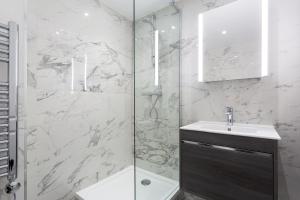 a bathroom with a sink and a glass shower at The Carlyle - Stunning Serviced Apartments in London +131 photos