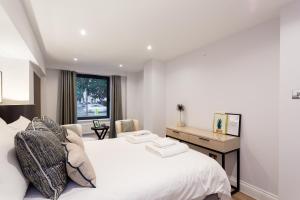 a bedroom with a white bed and a desk at The Carlyle - Stunning Serviced Apartments in London