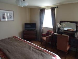 a bedroom with a bed and a television and a window at The Groes Inn in Conwy