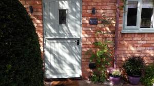 a gray door on a brick house with plants at Bijou Malthouse in Alcester