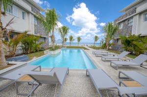 a swimming pool with chaise lounge chairs next to a building at L'Escale 3 bedrooms Sea View and Beachfront Suite by Dream Escapes in Tamarin