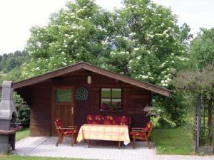 uma cabana com uma mesa e cadeiras à sua frente em Ferienwohnungen Baur em Arnbruck