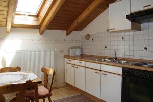 uma cozinha com armários brancos, uma mesa e uma janela em Ferienwohnungen Baur em Arnbruck