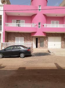 ein schwarzes Auto, das vor einem rosa Haus parkt in der Unterkunft Rooming house in Espargos