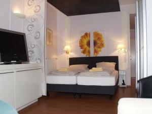 a bedroom with a bed with a flat screen tv at HOTEL alt lüneburger Kutscherstuben in Lüneburg