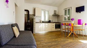 a living room with a couch and a table and chairs at Apartmani Ivana in Cres