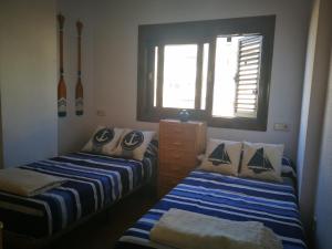 sypialnia z 2 łóżkami, oknem i nartami w obiekcie Las Alas del Mar. w mieście La Manga del Mar Menor