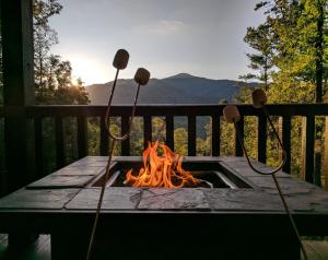 eine Feuerstelle auf einer Terrasse mit einem Tisch und einem Kamin in der Unterkunft Smokies Overlook Lodge in Waynesville