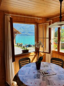 ein Esszimmer mit einem Tisch und einem großen Fenster in der Unterkunft Chalet Diana Lakefront in Ringgenberg