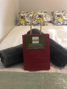 a red shopping bag sitting on top of a bed at The Square 11 Private Suite in Port Elizabeth