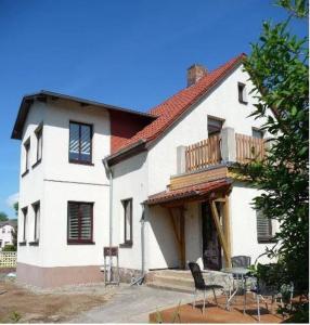 a white house with a balcony and a table at Ferienwohnung Ida in Ahlbeck