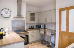 a kitchen with white cabinets and a clock on the wall at Harlow apartment in Harrogate
