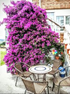 a table and chairs in front of a large wall of purple flowers at Apartamentos La Pradera de Isla in Isla