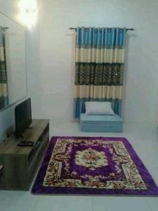 ein Wohnzimmer mit einem Teppich, einem Bett und einem TV in der Unterkunft Seri Kenangan in Kota Samarahan