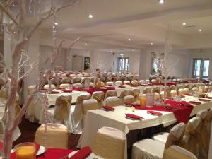 a large banquet hall with white tables and chairs at The Connaught Hotel Wolverhampton in Wolverhampton