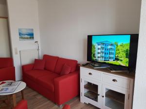 een woonkamer met een rode bank en een flatscreen-tv bij Studio 14 Strandmuschel, Residenz Seeblick in Ostseebad Sellin