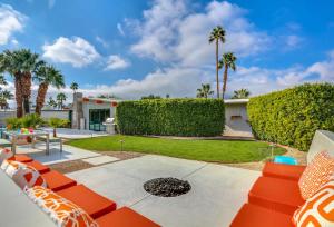 eine Terrasse mit Orangenmöbeln und Palmen in der Unterkunft Iconic Mid-century Modern Vacation Home with Pool! in Palm Springs