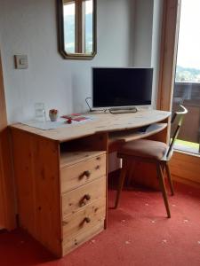 a wooden desk with a monitor and a chair at Pension Feiersinger in Kitzbühel