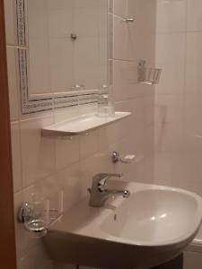 een witte badkamer met een wastafel en een spiegel bij Pension Feiersinger in Kitzbühel