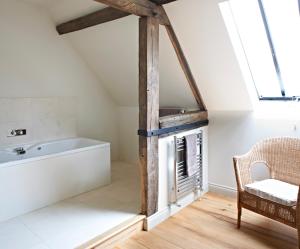 a bathroom with a bath tub and a chair at Manor Farm Courtyard Cottages in Hampstead Norris