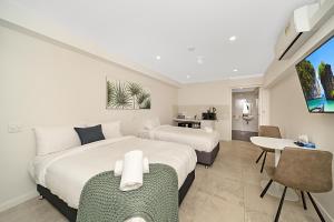 古尔本Carlton Suites的一间卧室，有两张床、一张桌子和几把椅子