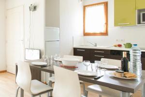 een keuken met een tafel met witte stoelen en een keuken met bij Résidence Le Chalet de L'Eterlou by Popinns in Saint-Chaffrey