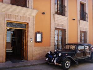 un viejo coche negro estacionado frente a un edificio en Hospedería Bodas de Camacho, en Munera