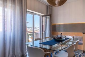 une salle à manger avec une table en verre et des chaises blanches dans l'établissement LovelyStay - Sunshine Residence in the Heart of Graça, à Lisbonne
