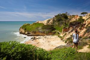 a woman standing on a cliff looking at the ocean at PortoBay Falesia in Albufeira