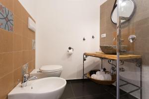 ein Badezimmer mit einem Waschbecken, einem WC und einem Spiegel in der Unterkunft Pura Vida Iblea in Ragusa