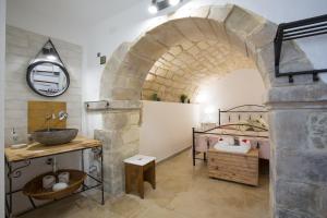 un bagno con lavandino e un letto in una camera di Pura Vida Iblea a Ragusa