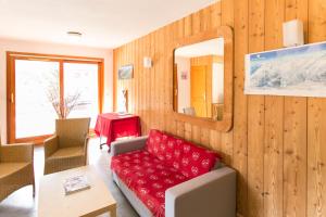 a living room with a red couch and a mirror at Résidence Le Chalet de L'Eterlou by Popinns in Saint-Chaffrey