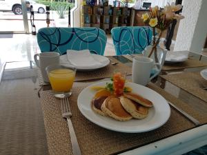 a table with a plate of pancakes and orange juice at Nirvana Hotel - Cancun Hotel Zone in Cancún