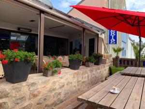 a patio with potted plants and a table and an umbrella at Le Trymen in Saint-Guénolé