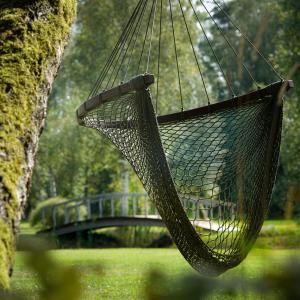 a hammock hanging from a tree in a park at Kupolmāja Ārpus laika - Domehouse in the forest in Tīnūži