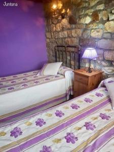 a bedroom with two beds and a stone wall at Casa Rural Juntana in Abionzo