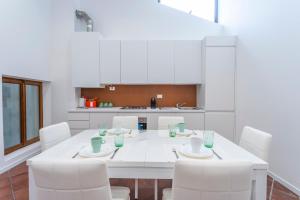 una cucina bianca con tavolo bianco e sedie bianche di Ricasoli Garden Modern Apartments a Udine